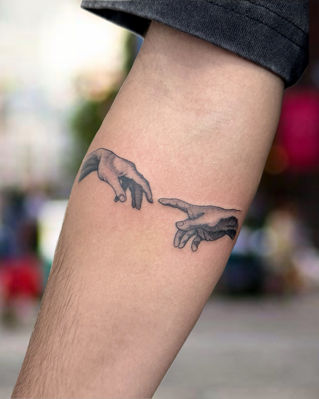 Black and grey Creation of Adam Michelangelo hands tattoo on forearm