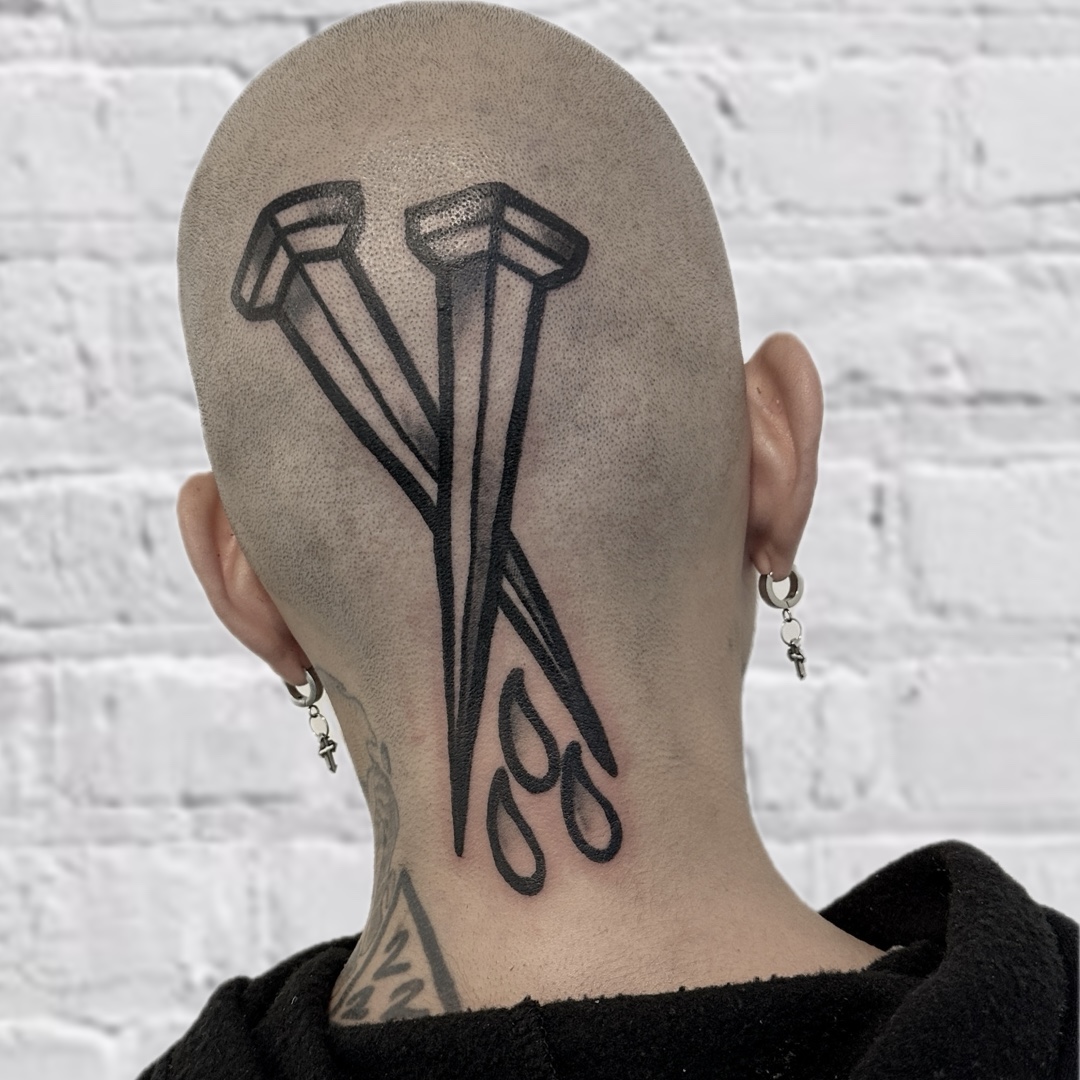 Bold black crossed nails scalp head tattoo